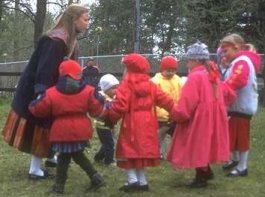 photo of a teacher and her students holding hands and orderly going around in a circle