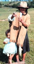 Photo of a Colombian peasant woman (spinning wool) and her granddaughter at her side